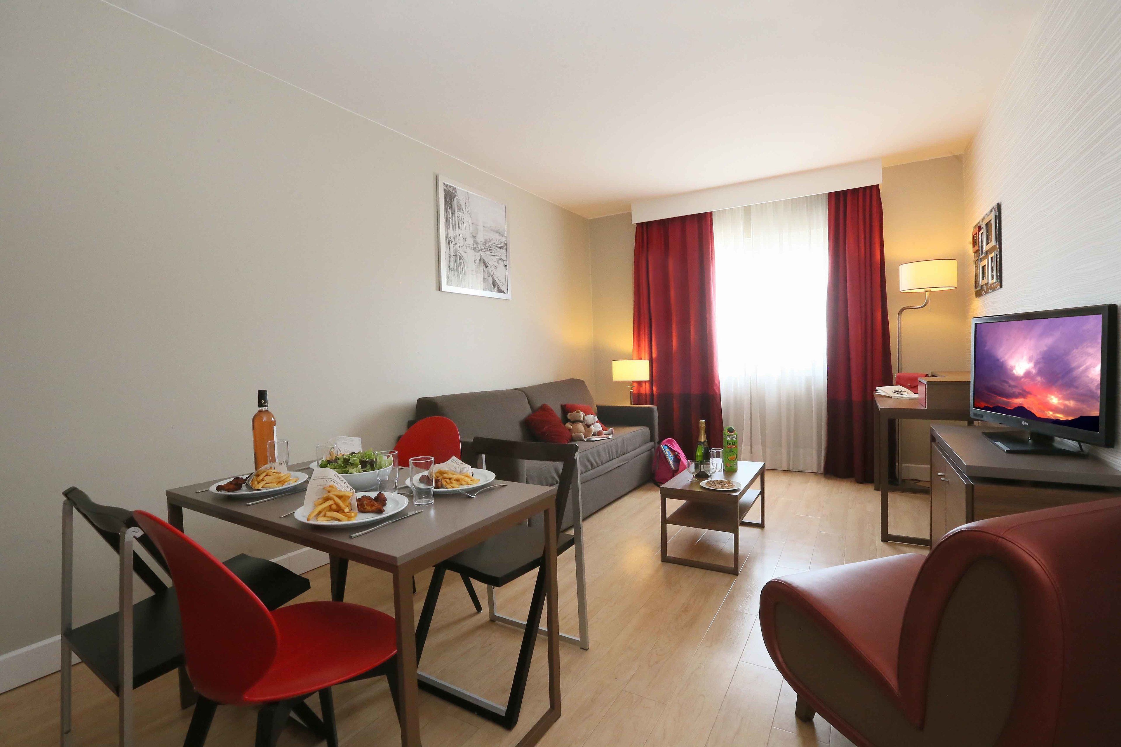 Ein modernes Wohnzimmer mit Essbereich, einer Couch, einem Fernseher und einem Tisch mit Speisen.