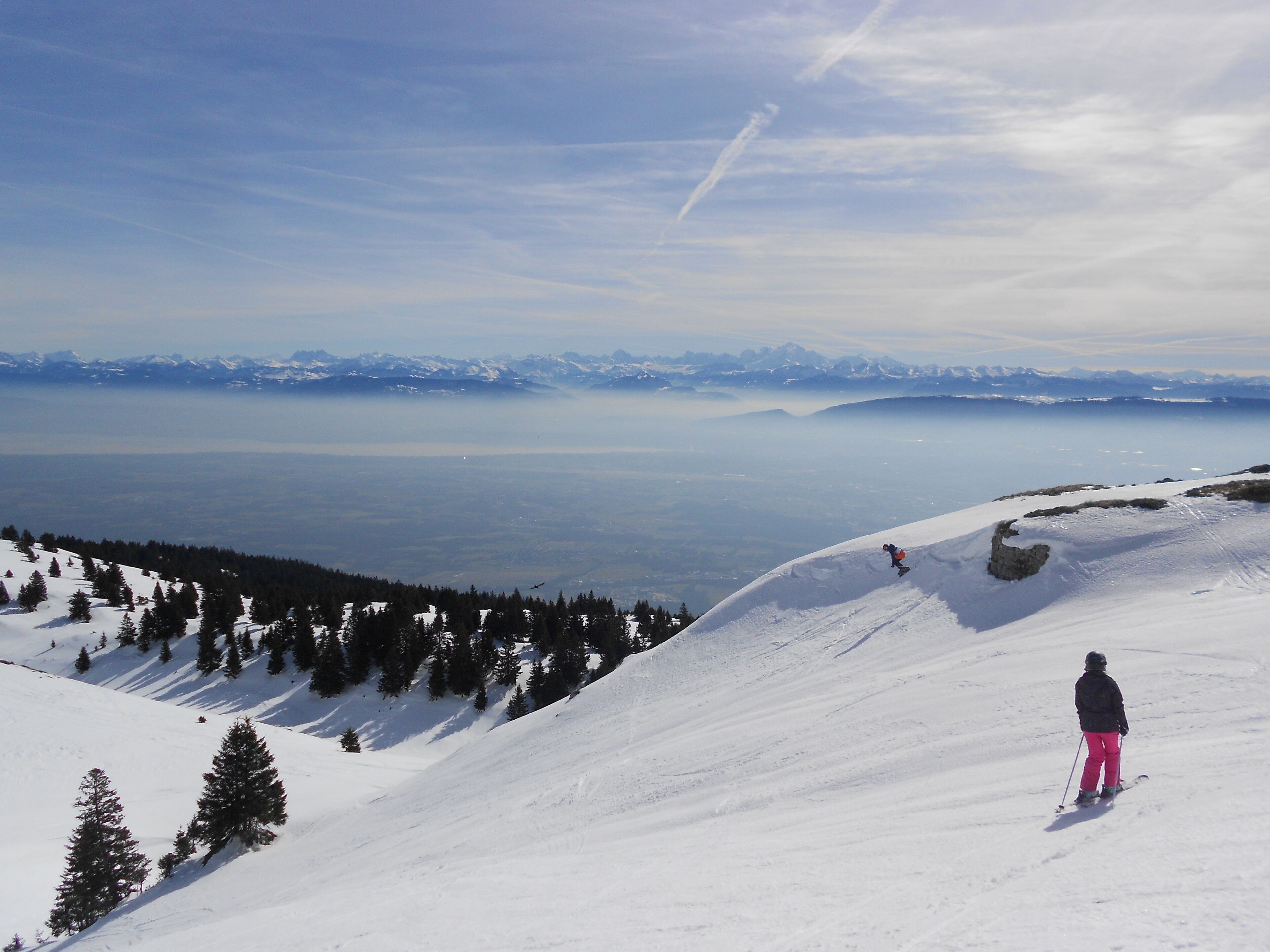 Un paysage de montagne enneigé avec un skieur sur une pente.