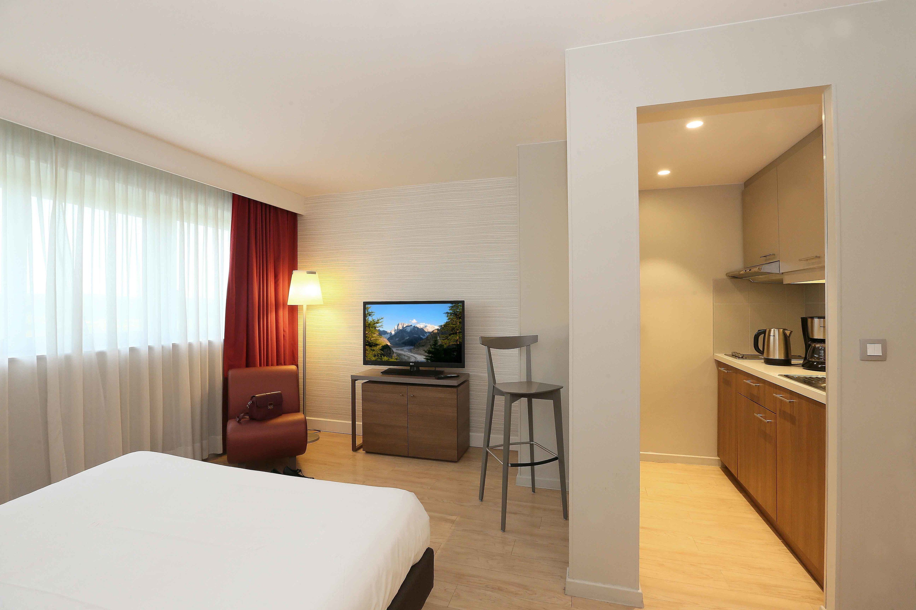 Une chambre d’hôtel équipée d’un lit, d’une télévision, d’un bureau, d’une chaise et d’une kitchenette.