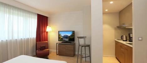 Une chambre d’hôtel équipée d’un lit, d’une télévision, d’un bureau, d’une chaise et d’une kitchenette.