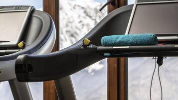 A treadmill with a towel and a charging cable, set against a snowy mountain backdrop.