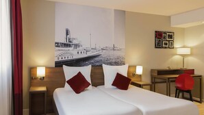 Une chambre d’hôtel avec un grand lit, deux tables de chevet avec des lampes, un bureau et une chaise.