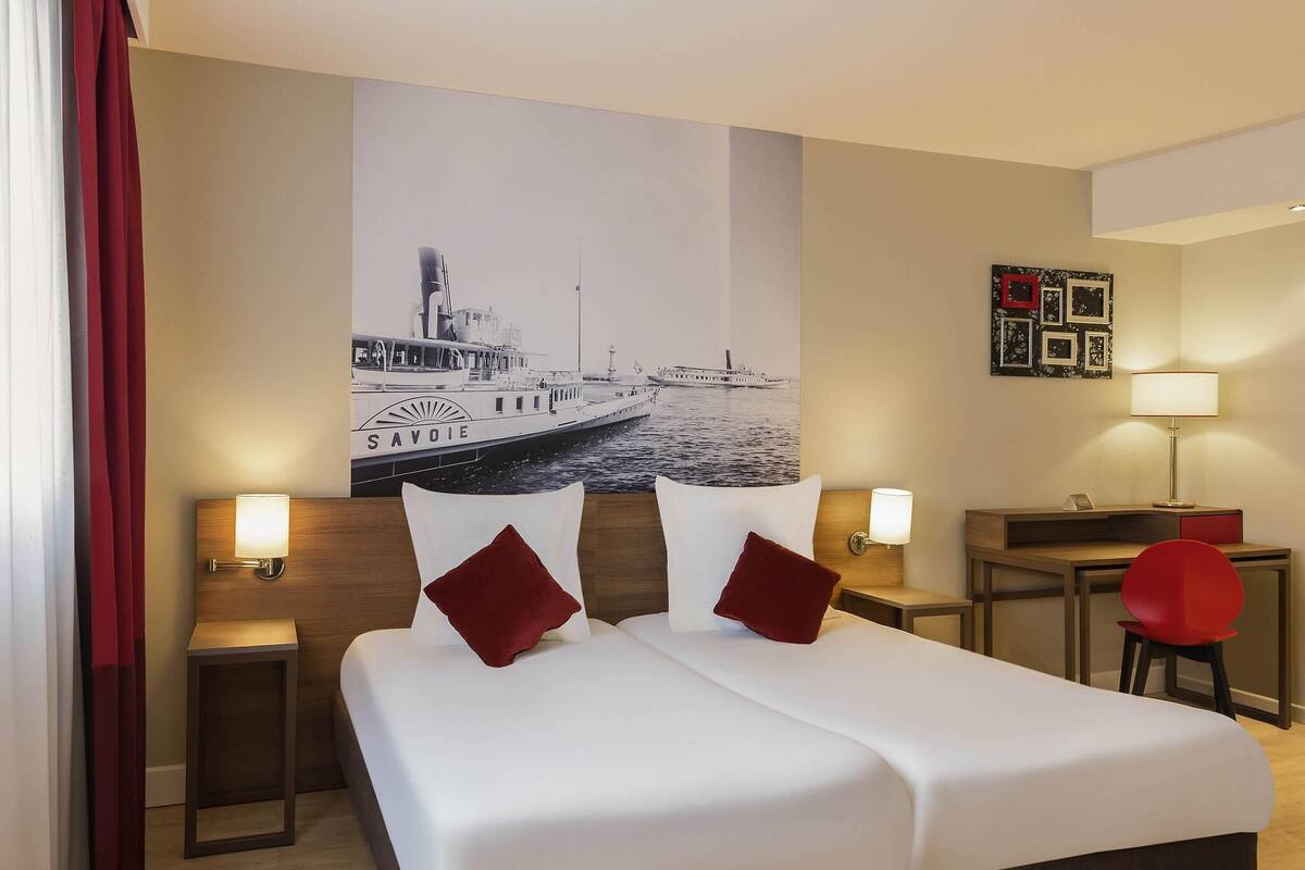 Een hotelkamer met een groot bed, twee nachtkastjes met lampen, een bureau en een stoel.