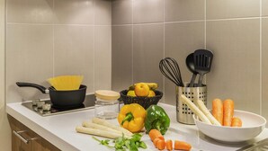 Une cuisine équipée d’une cuisinière, d’ustensiles et de légumes frais.