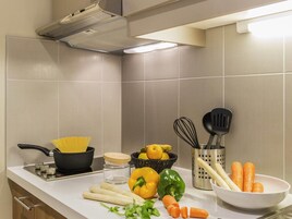 Uma cozinha com fogão, utensílios e legumes frescos.