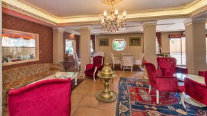 Eine Hotelhalle mit einem roten Sofa, einer Kandelaber und einem traditionellen Teppich.