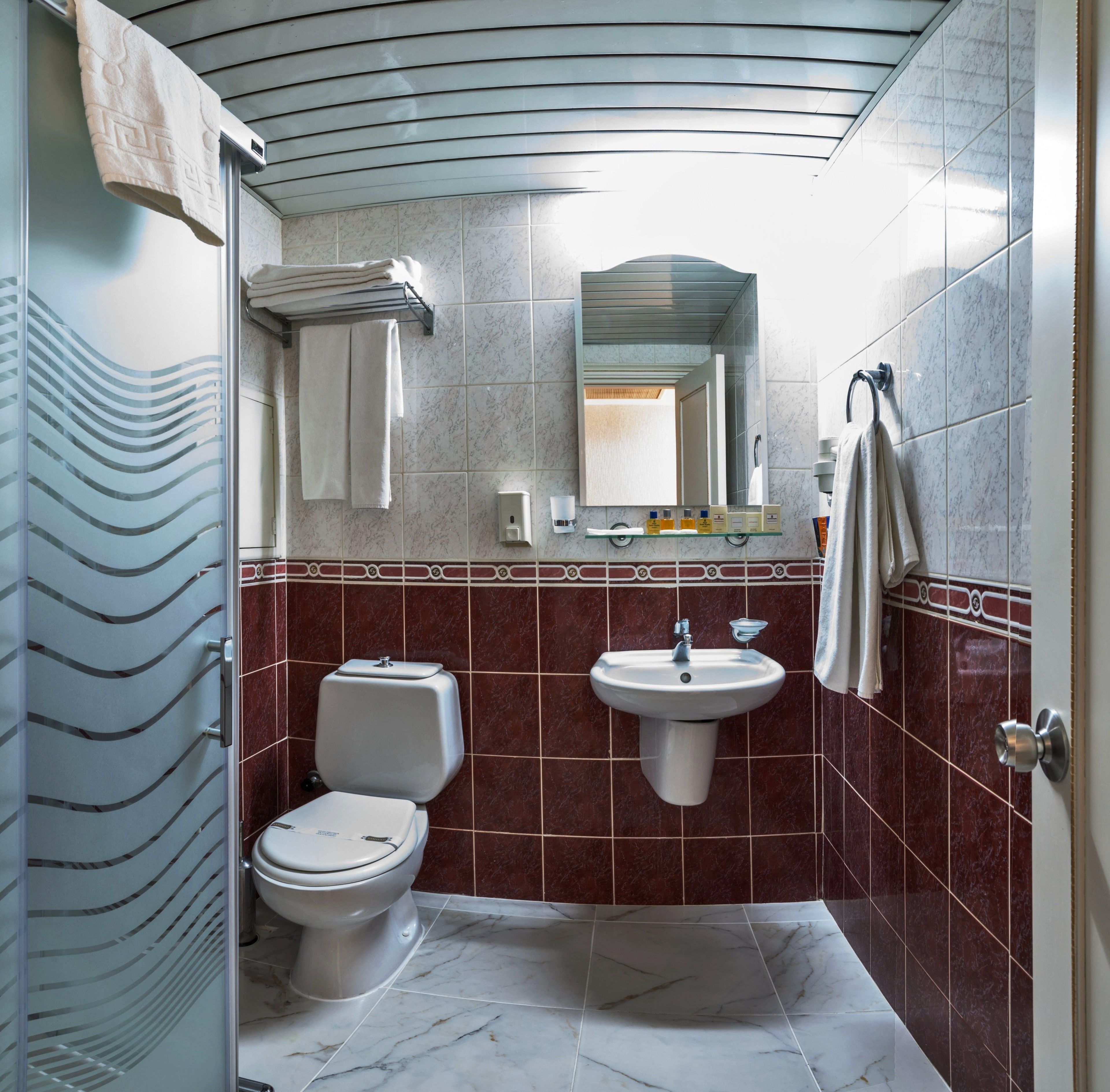 A bathroom with a toilet, sink, and mirror.