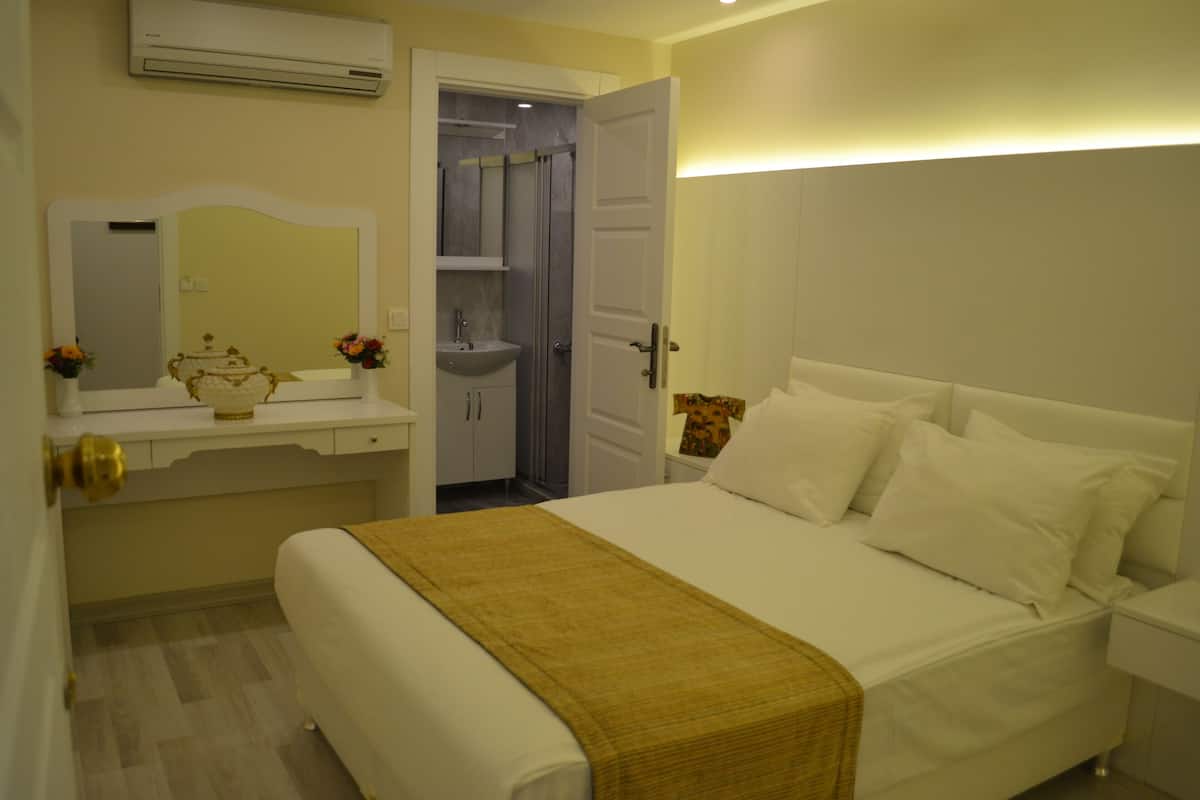 A hotel room with a bed, bedside table, and a bathroom visible through an open door.