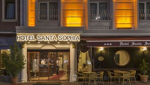 Das Hotel Santa Sophia mit einem prunkvollen Eingang, einer gut beleuchteten Fassade und einer Sitzgelegenheit im Freien.