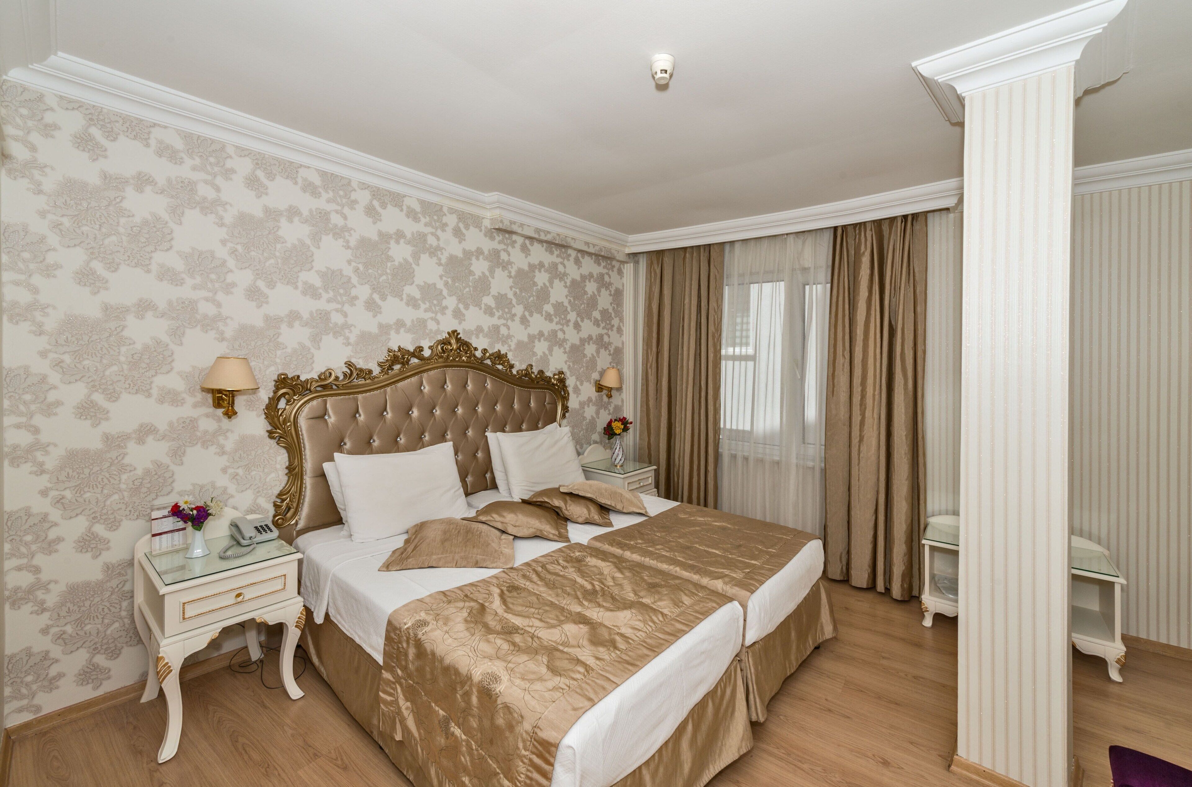 A hotel room with a large bed, two bedside tables, a nightstand, and a chair.