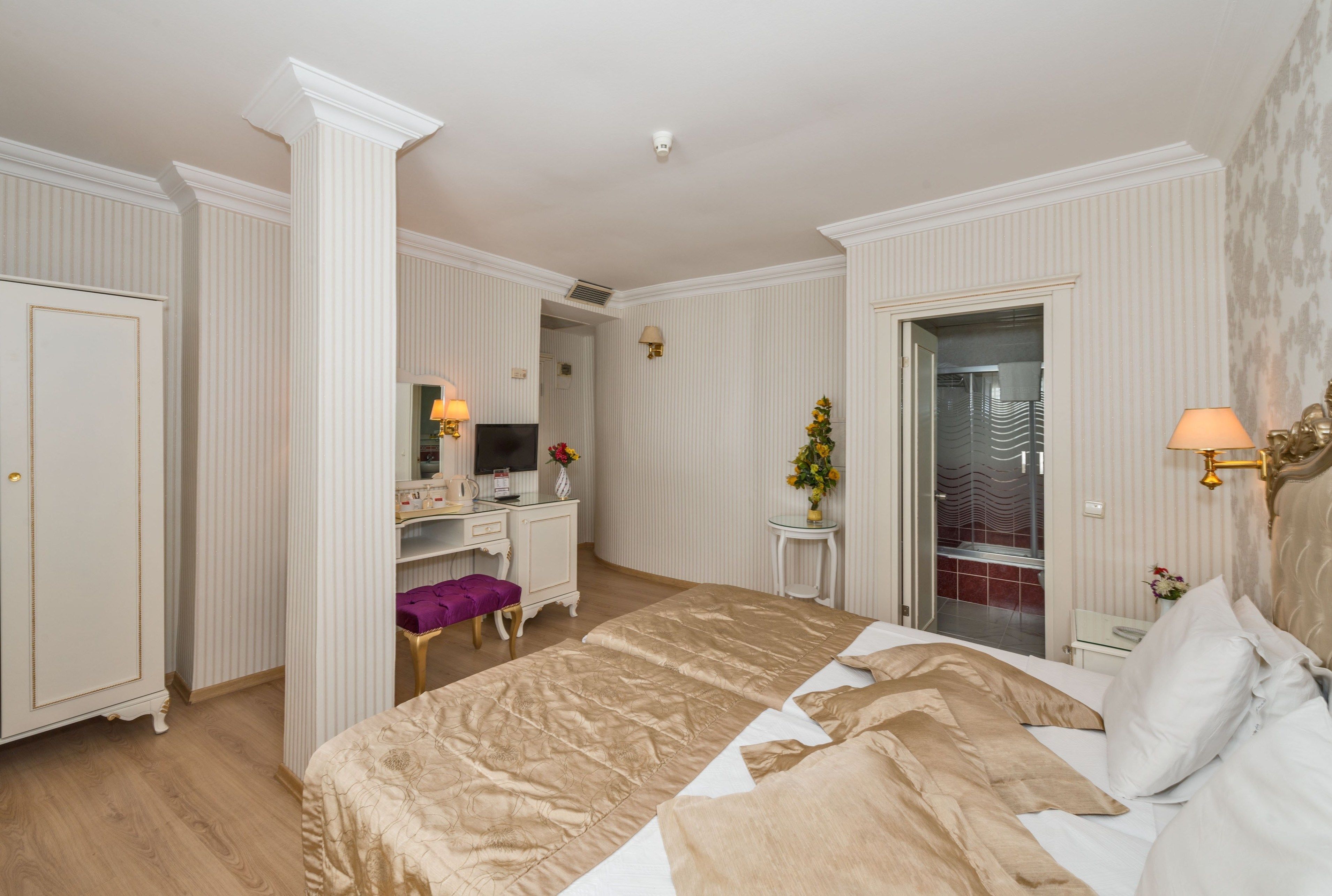 Ein Hotelzimmer mit einem großen Bett, einem Schreibtisch mit Stuhl, einem Schminktisch und einem durch eine offene Tür einsehbaren Badezimmer.