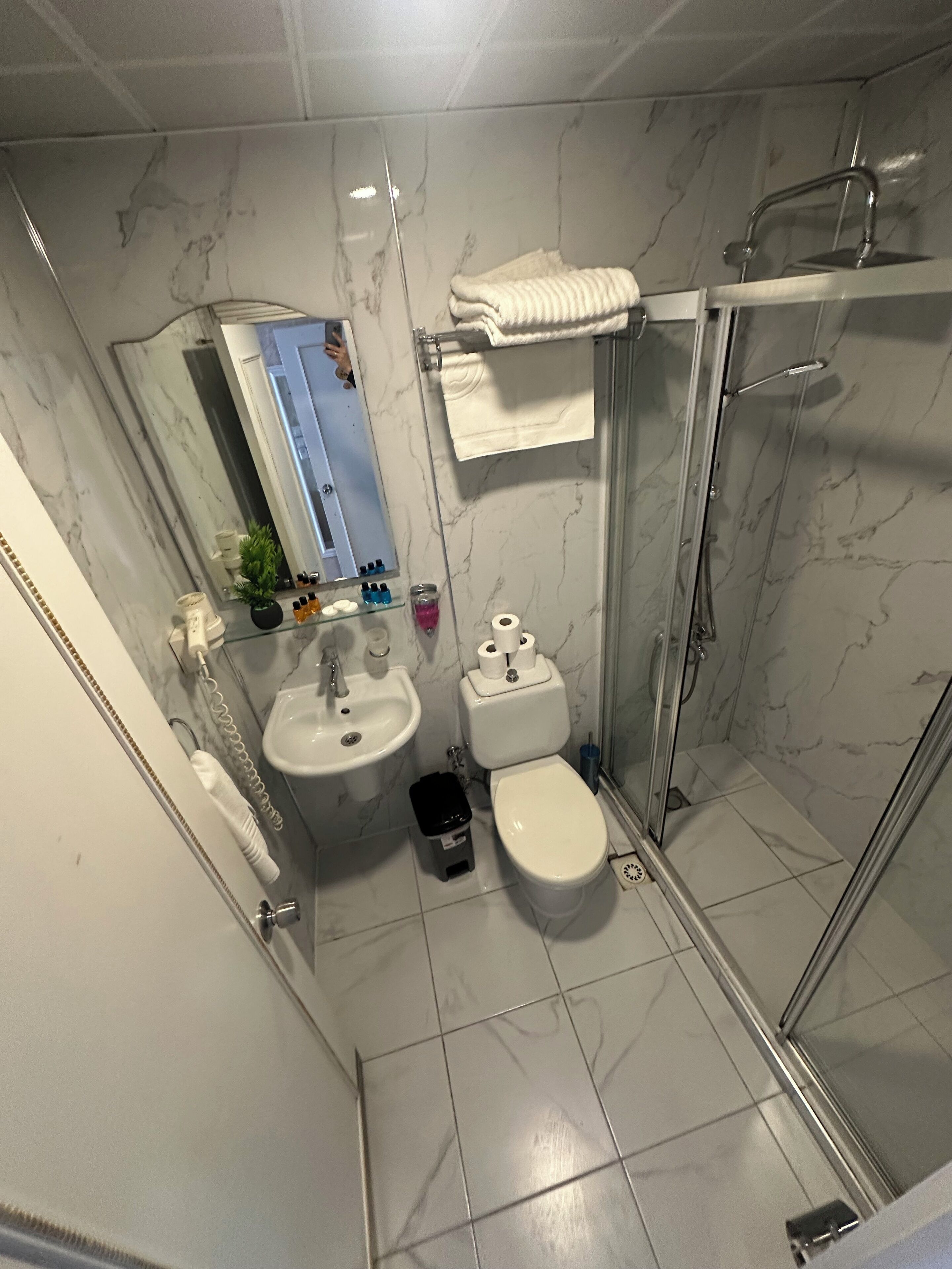 Ett badrum med en handfat av marmor, toalett och en duschavdelning med glasväggar.