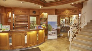 Un vestíbulo de hotel con un mostrador de recepción de madera, un reloj y una escalera.