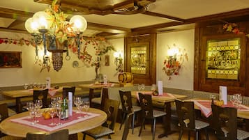 A restaurant with round tables, chairs, and a chandelier.