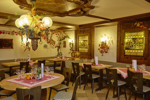 Un restaurante con mesas redondas, sillas y una araña.