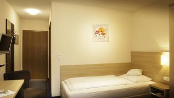 Ein Hotelzimmer mit Bett, Schreibtisch, Stuhl, Fernseher und einem Bild an der Wand.