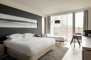 Una camera d'albergo moderna con un letto grande, un letto più piccolo, una scrivania e una sedia.