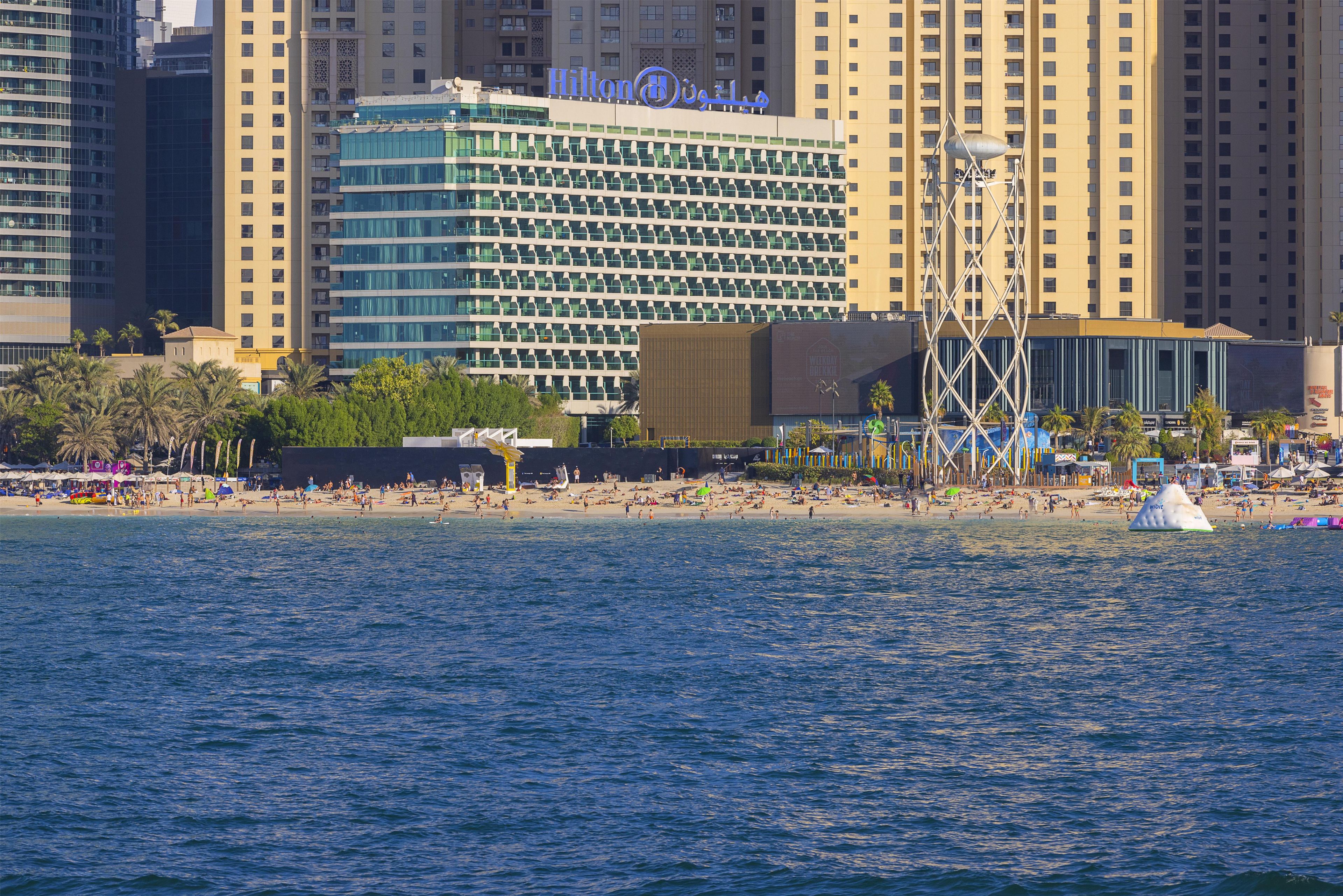 A hotel with a modern design, located near a beach with a view of the ocean.