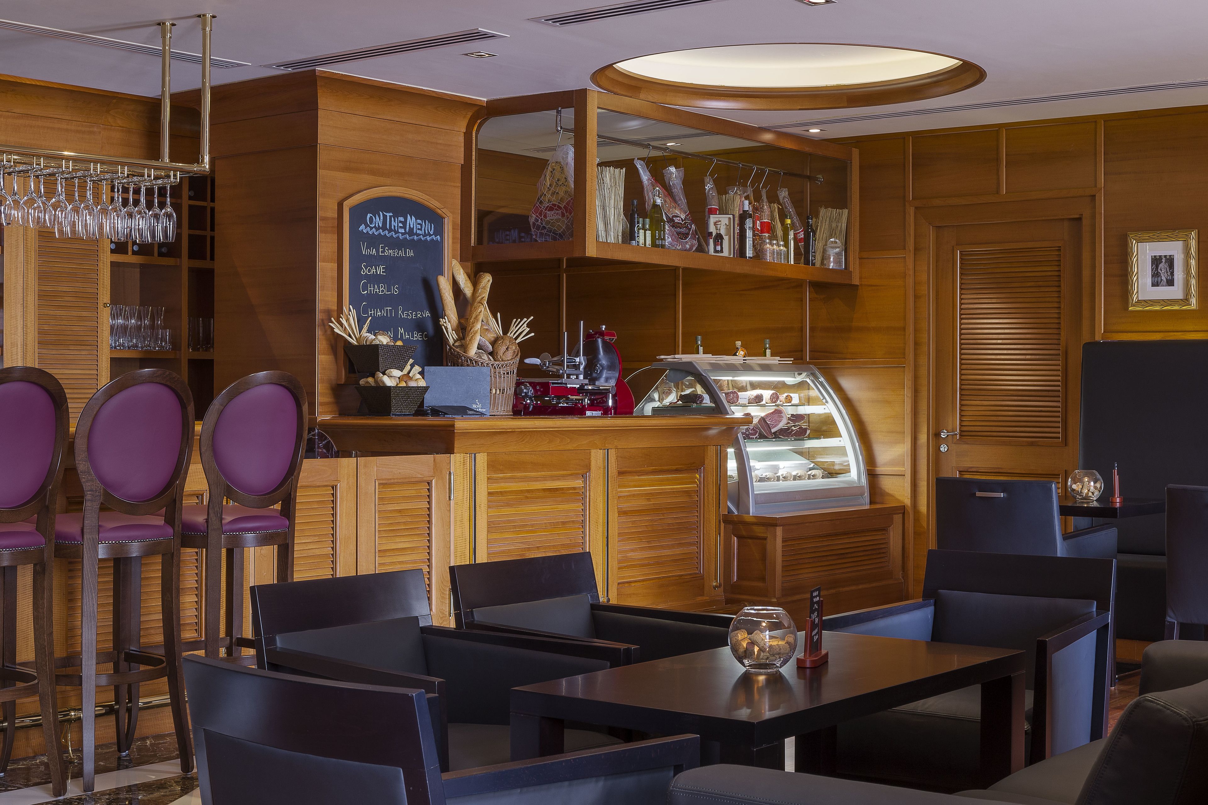 Un restaurant au décor en bois, avec un menu écrit à la craie et proposant différents types de sièges, notamment des tabourets de bar et des tables.