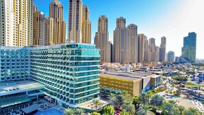 A modern hotel with a pool, surrounded by palm trees and high-rise buildings. - Hilton Dubai Jumeirah (Dubai)