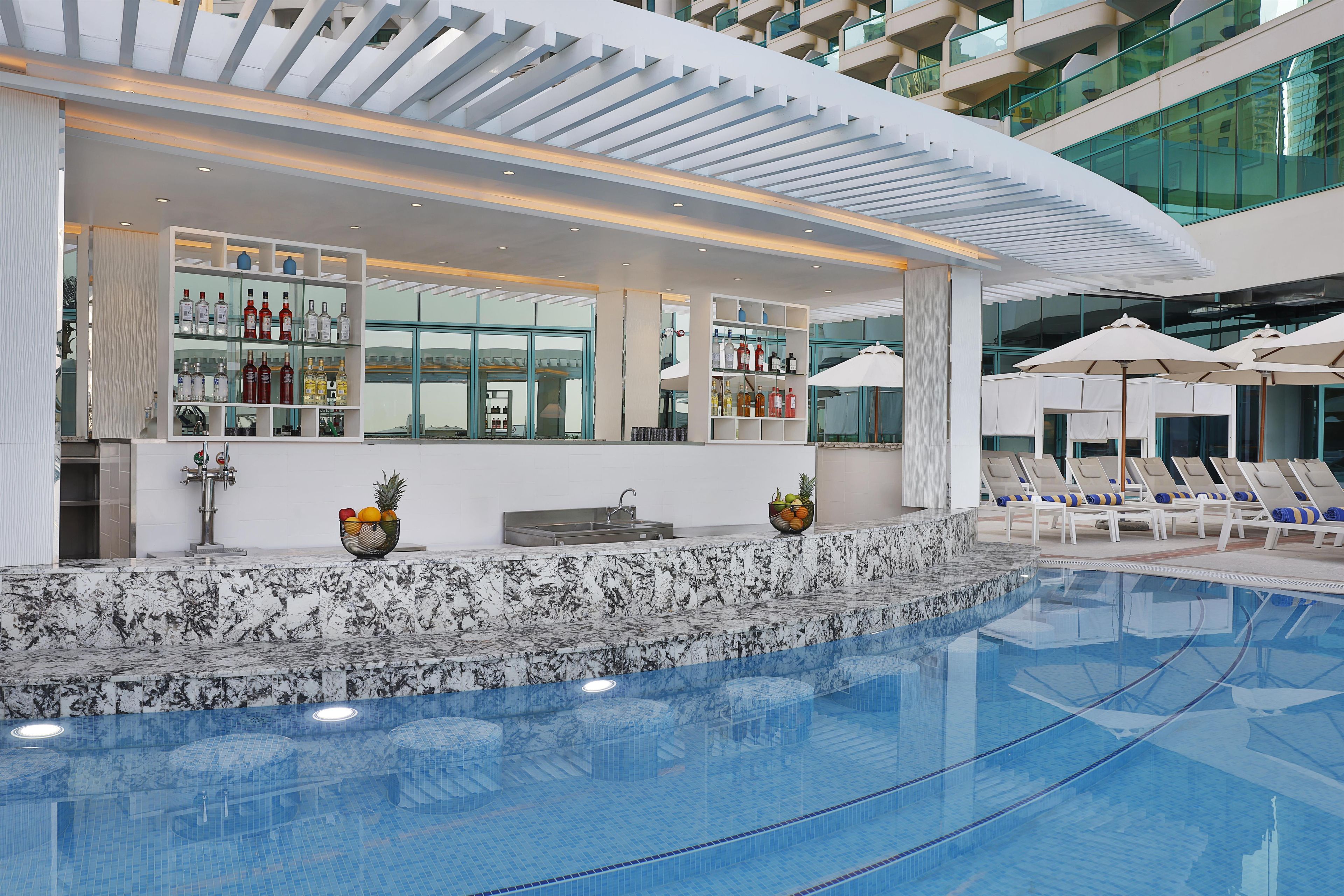 A modern indoor pool area with a bar, lounge chairs, and a clear view of the pool.