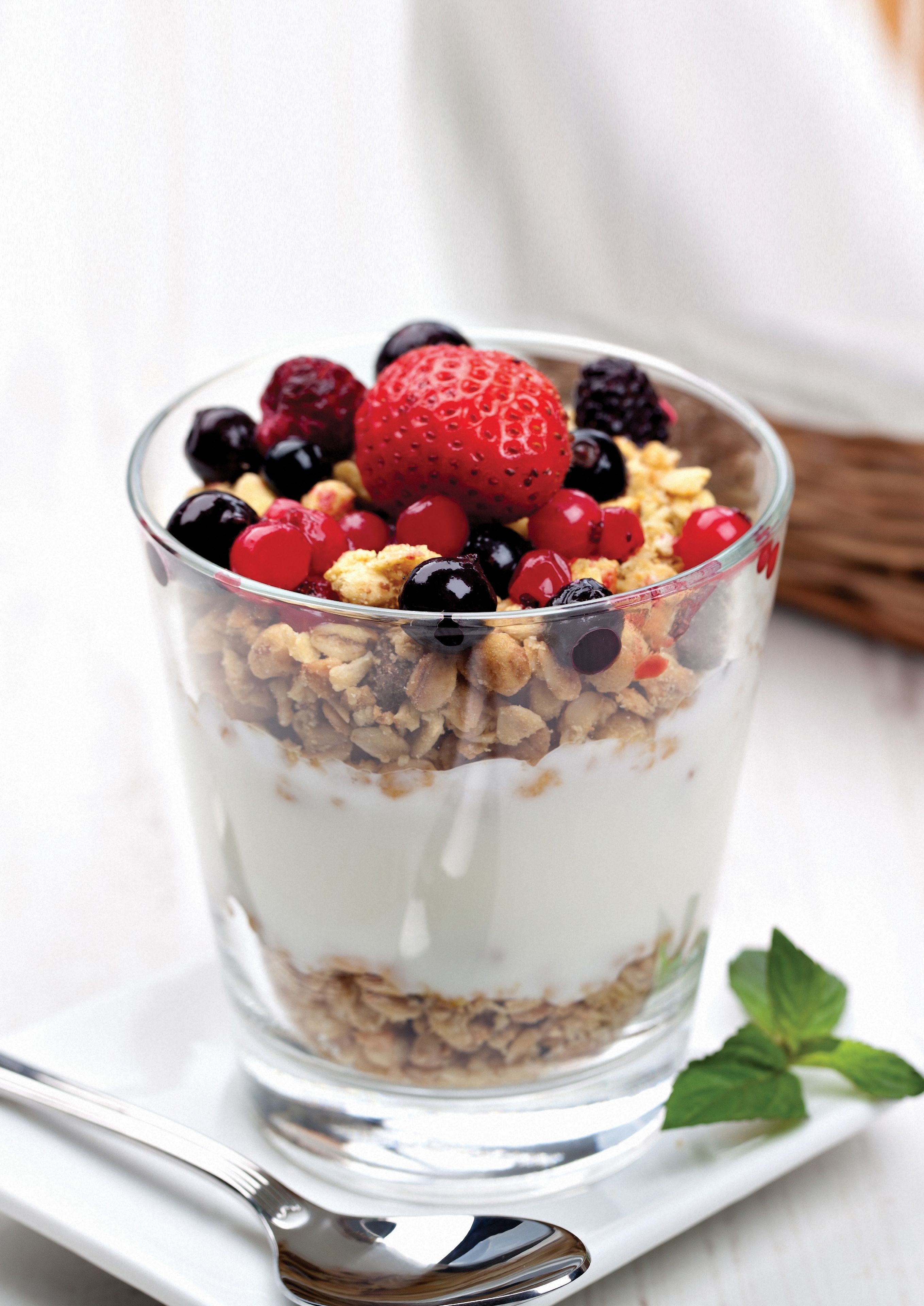A clear glass dessert with layers of yogurt, granola, and berries.