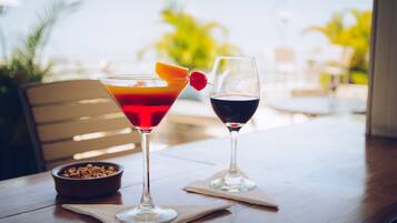 Dos bebidas sobre una mesa de madera con un tazón de cereales y una silla al fondo.