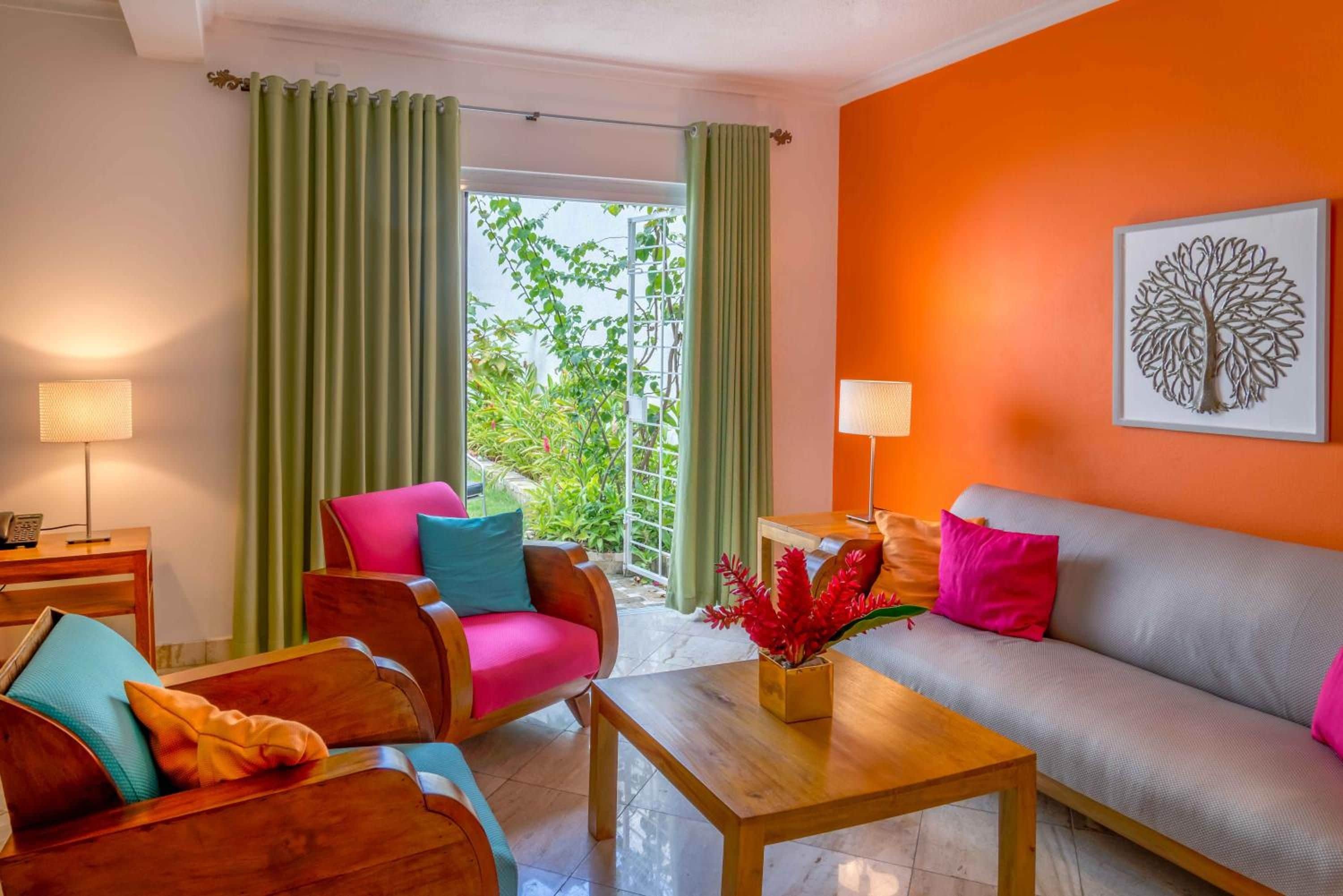 A living room with a sofa, chairs, a coffee table, and a view of greenery outside.