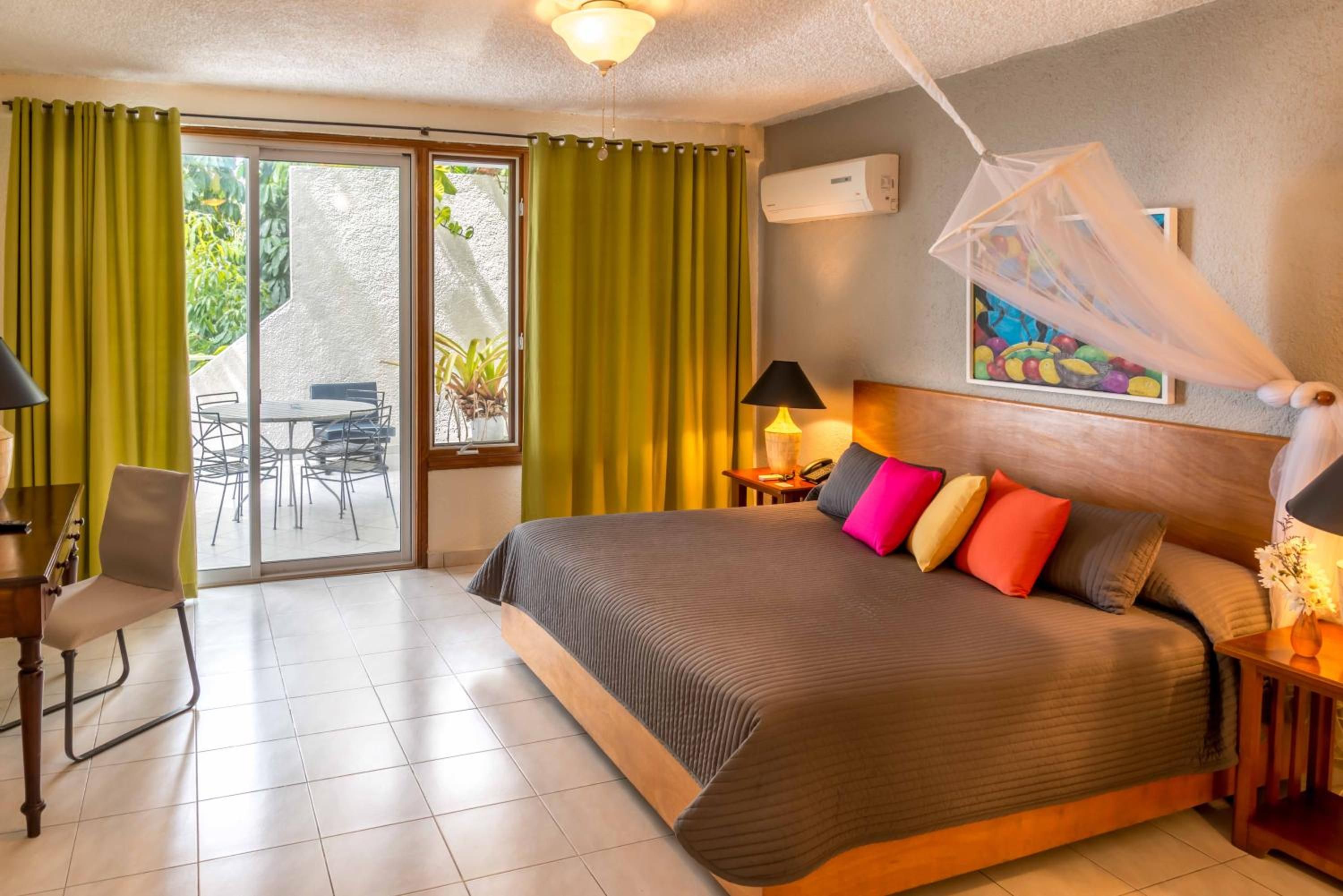 A hotel room with a bed, a desk, a chair, a table, and a view of the outdoors.