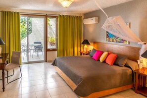 A hotel room with a bed, a desk, a chair, a table, and a view of the outdoors.