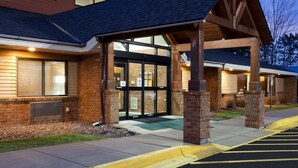A building with a brick facade, large glass entrance, and a covered porch area. - AmericInn by Wyndham Mora (Mora)