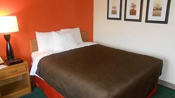 A neatly made bed with a brown cover, a bedside lamp, and a wooden nightstand with a telephone.