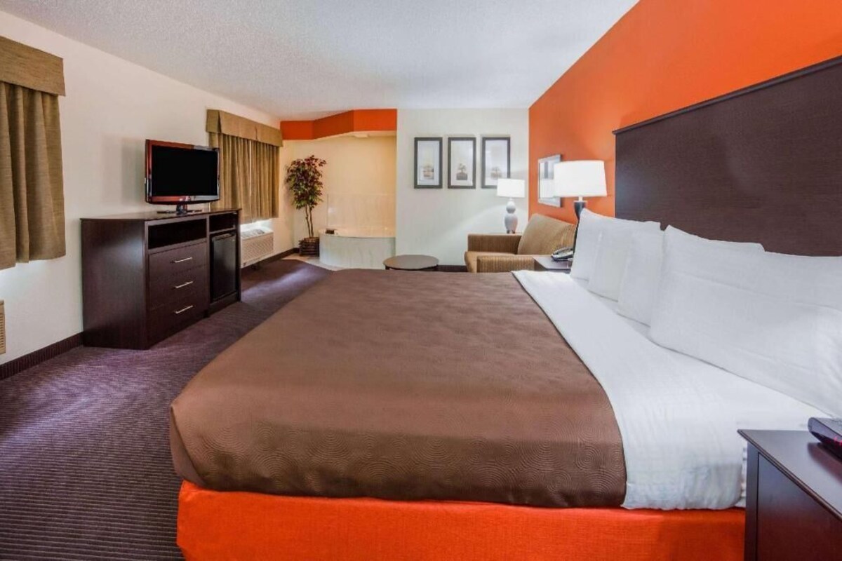 A hotel room with a large bed, a television, a desk, and a chair.