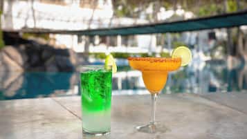 Two drinks on a table by a poolside.