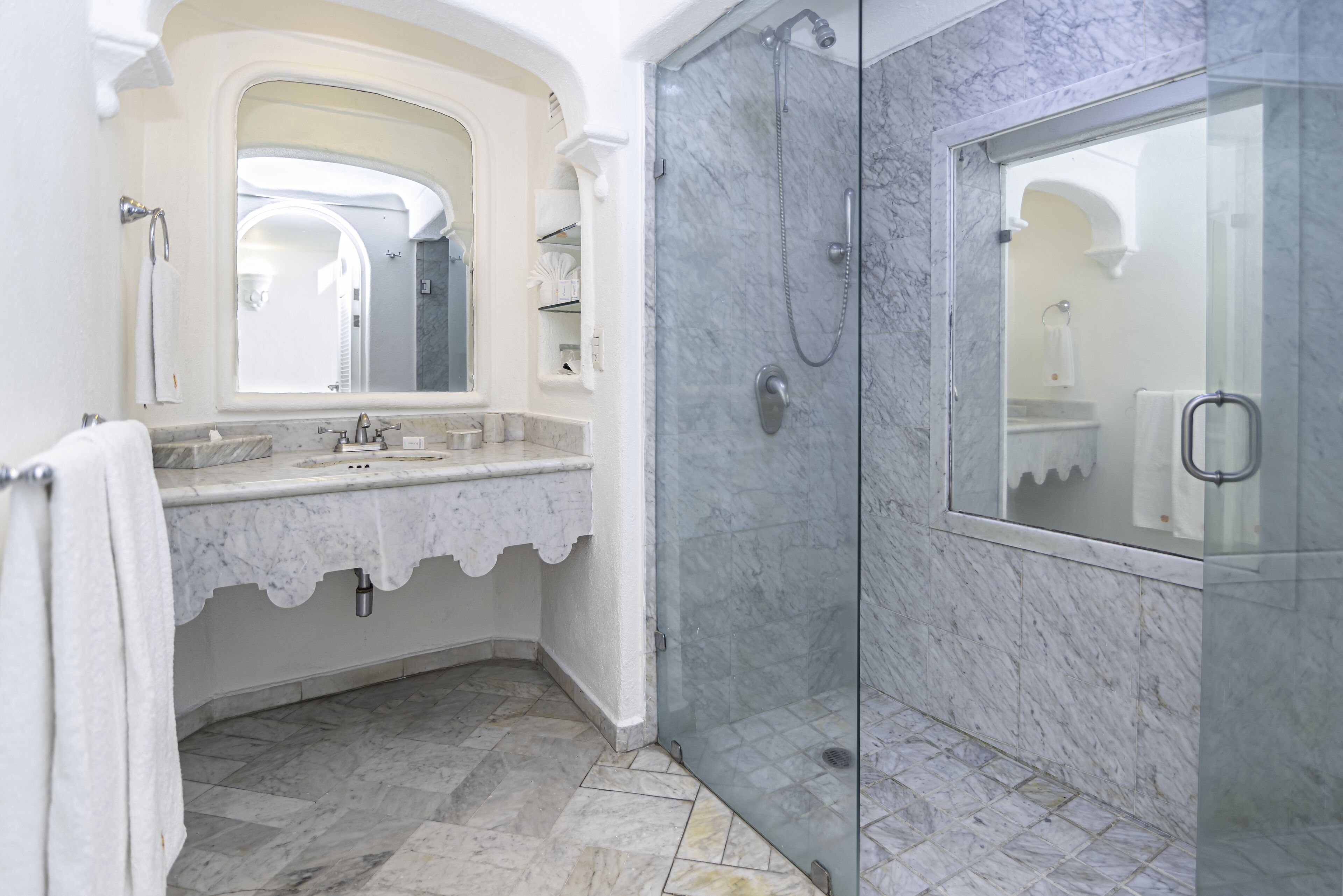 A bathroom with a marble sink, a glass-enclosed shower, and a large mirror.