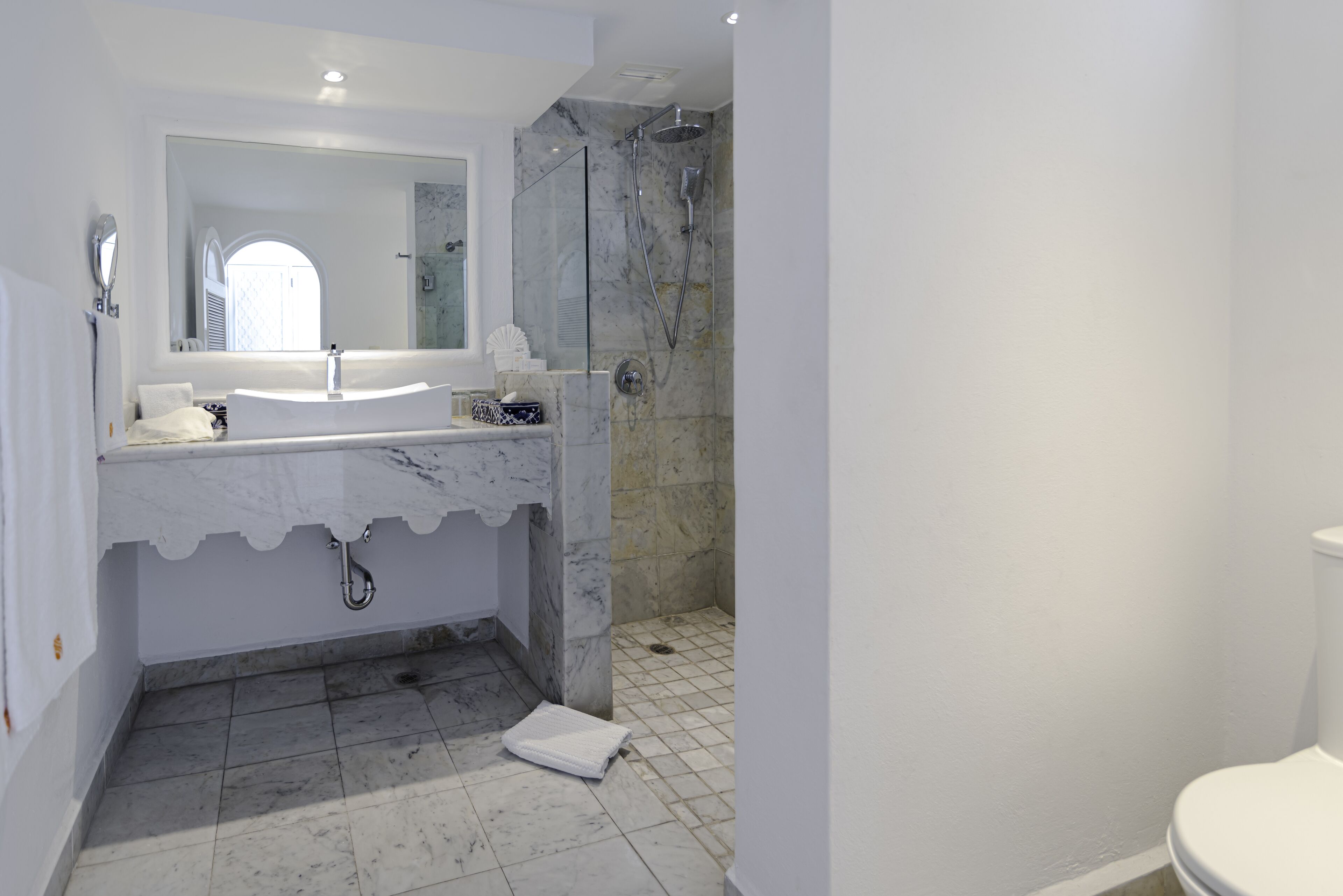 A modern bathroom with a marble sink, a large mirror, and a shower area.