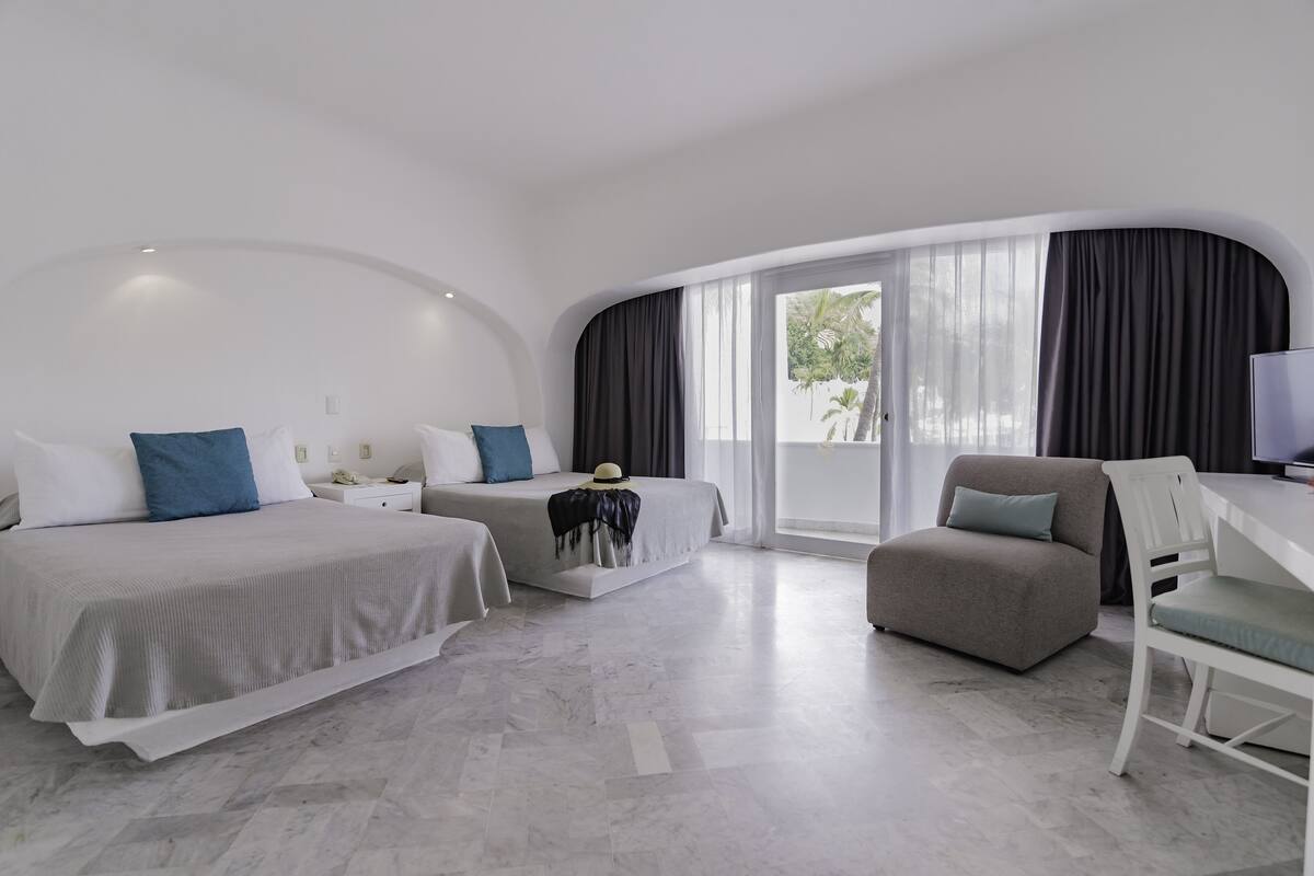 Una habitación de hotel moderna con una cama grande, una cama más pequeña, un sofá y un escritorio.