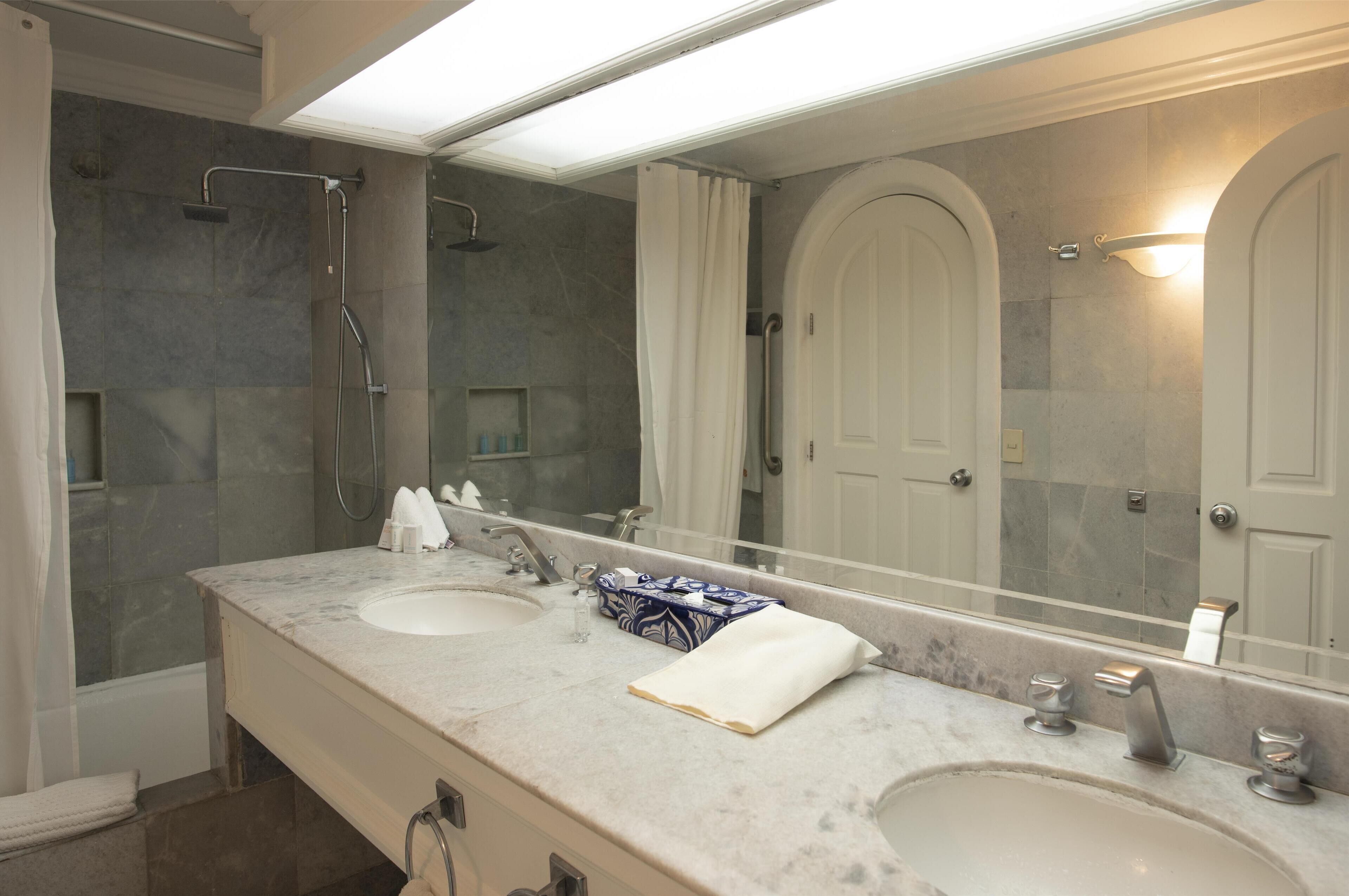 Ein Badezimmer mit zwei Waschbecken, einer Dusche und einem großen Spiegel.