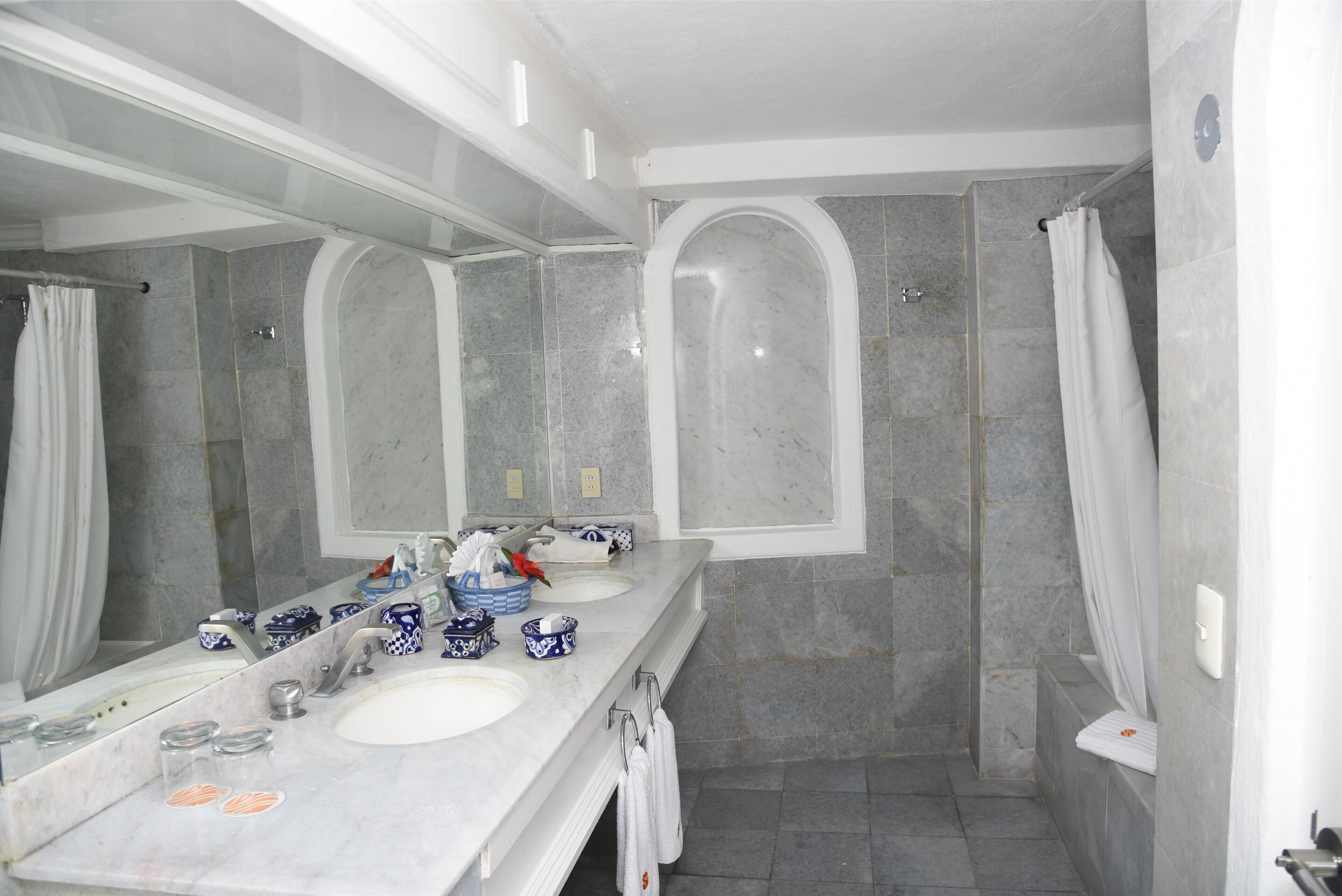 Un baño con un espejo grande, dos lavamanos, ducha y bañera.