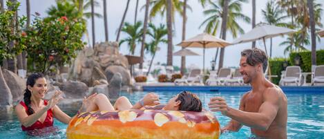 A pool area with lounge chairs and umbrellas, surrounded by palm trees.