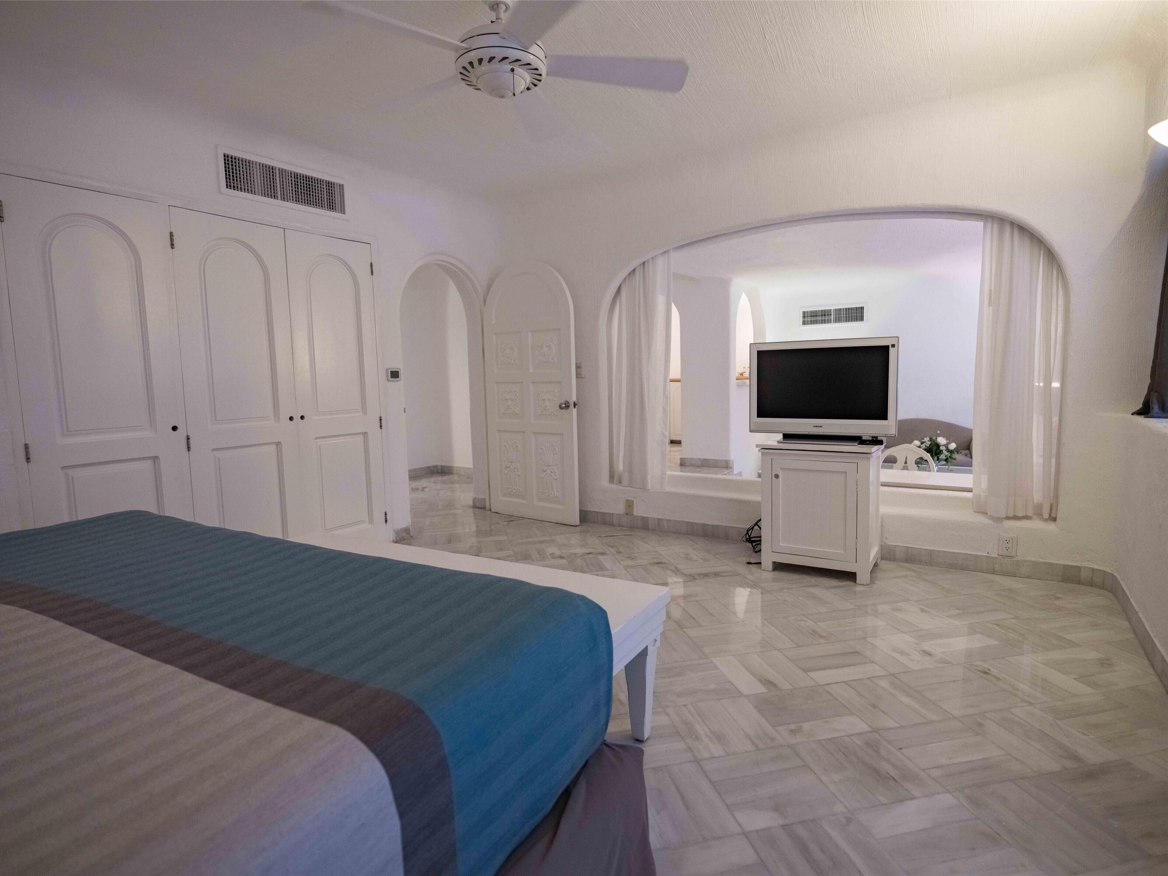 A hotel room with a bed, a television, and a desk.