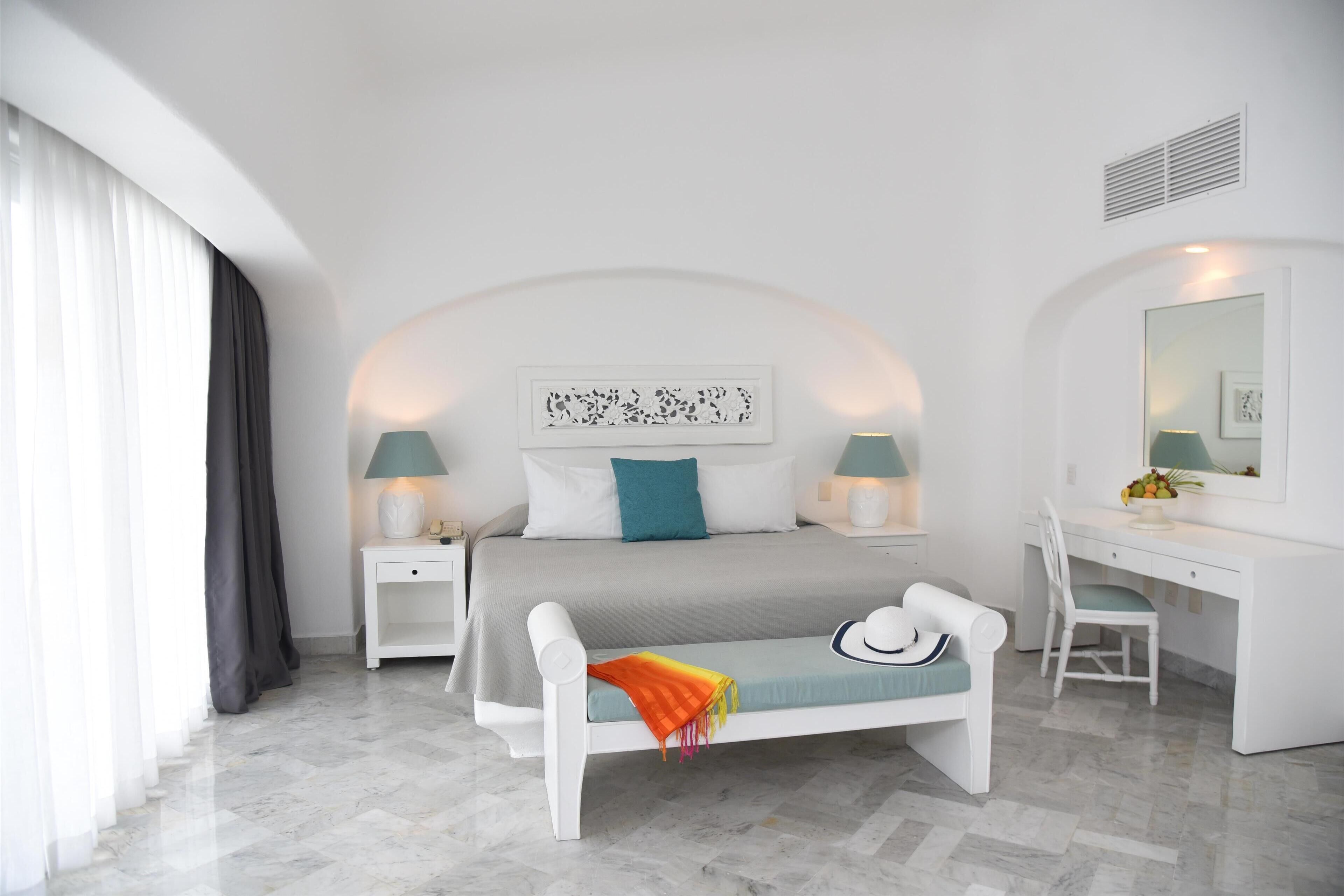 Una habitación de hotel moderna con cama, mesitas de noche, escritorio y una silla.