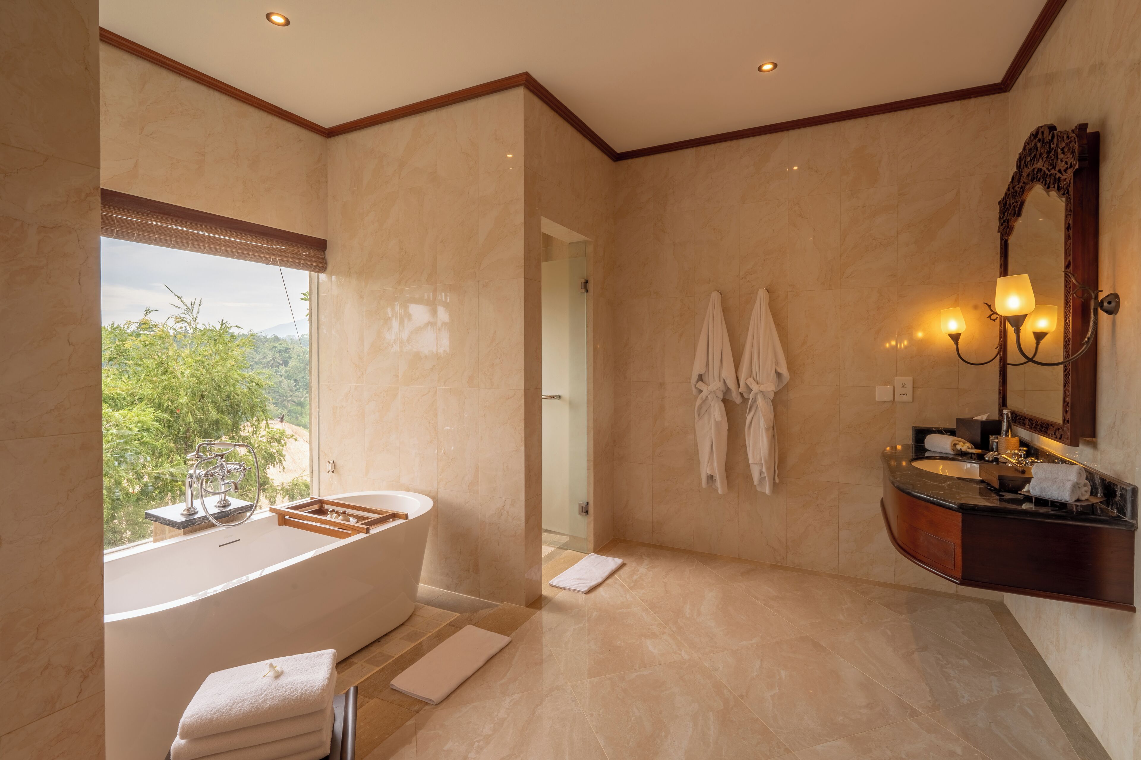 Un baño moderno con una bañera independiente, un tocador con espejo y vistas al exterior.