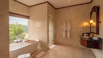 Un baño moderno con una bañera independiente, un tocador con espejo y vistas al exterior.