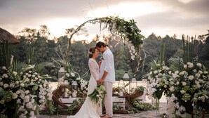 A couple embracing under a floral arch with greenery and lanterns. - Puri Wulandari a Boutique Resort and Spa (Ubud)