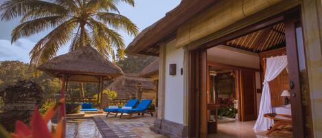 A resort with a pool area, lounge chairs, and a thatched-roof structure.