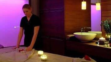 Experience a serene ambiance in this stylish room, featuring a massage table, large mirror, and sink.