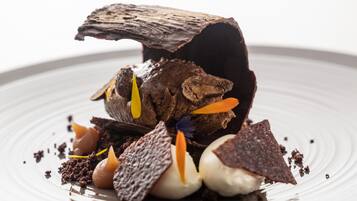 Un postre con detalles de chocolate y adornos sobre un plato.