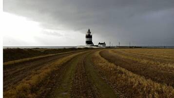 Um farol em um campo gramado com uma trilha de terra que leva até ele.