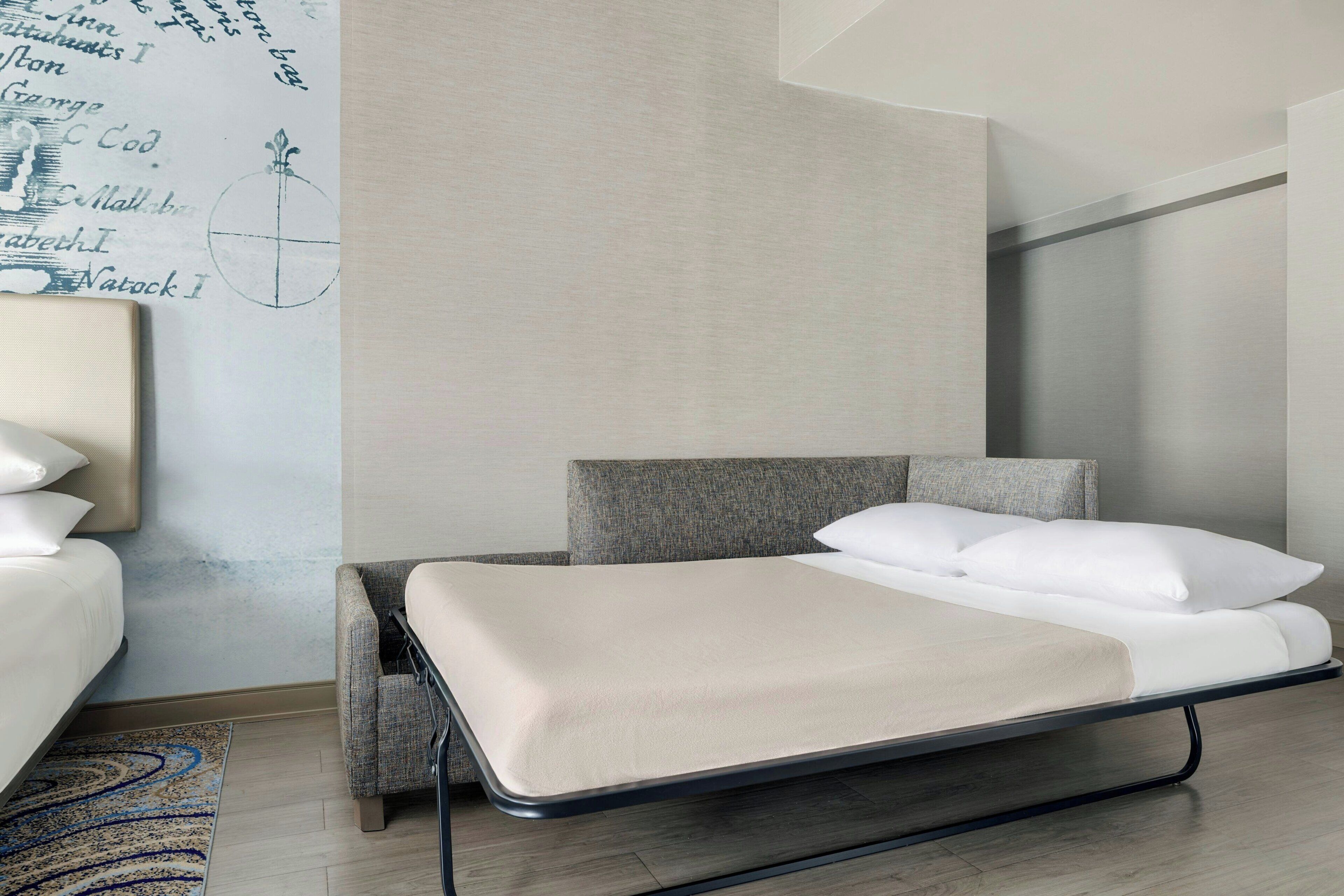Een moderne hotelkamer met een bed, een stoel, een klein tafeltje en een wand met een decoratieve kaart.